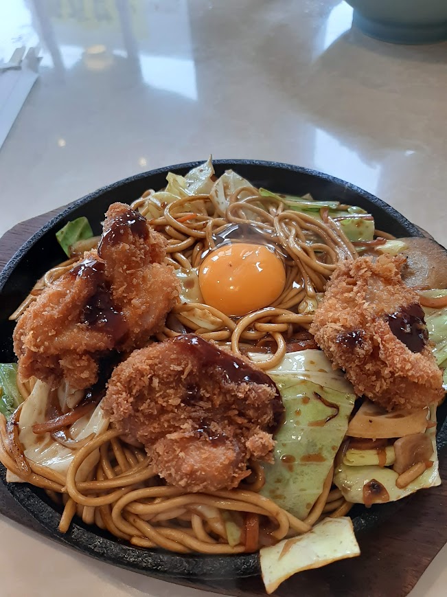 銀河のチャンポン。黒い鉄板の上に焼きそば。中央に卵黄。太麺で野菜多め。チキンカツ3個