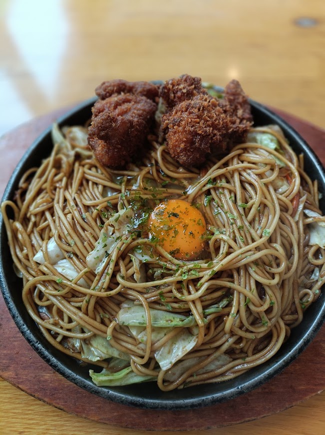 八幡のチャンポンの焼きそば。黒い鉄板の上に焼きそば。中央に卵黄。細麺、チキンカツ2個