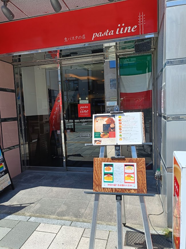 パスタイイネの外観。赤い看板とイタリア国旗が飾ってある。手前にメニュー。