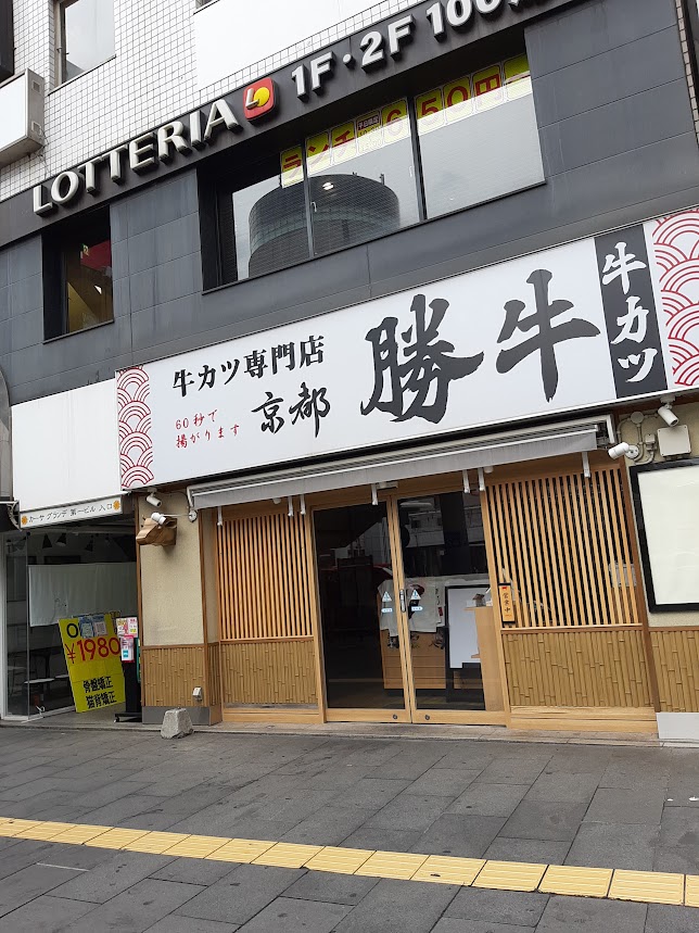 看板に大きく「勝牛」牛カツ専門店京都と書いた店舗の写真