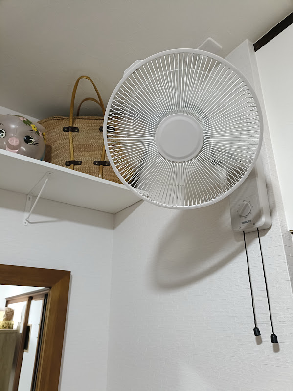 白い洋室の壁に付けられた壁掛け扇風機